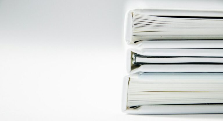 Three document binders stacked on a white surface.