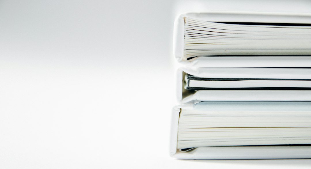 Three document binders stacked on a white surface.
